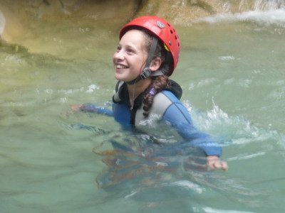 Kind met helm en wetsuit zwemt in een rivier tijdens canyoning in Mercantour & Vésubie, Frankrijk.