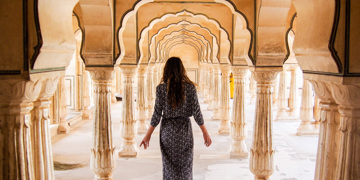Vrouw loopt door de bogen en zuilengang van Amber Fort in Jaipur.