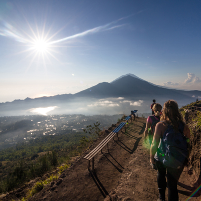 Wandelaars op de bergkam tijdens de beklimming van Mount Batur bij zonsopkomst, met uitzicht op de vulkaan.