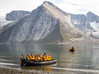 Zodiac-excursie met reizigers in gele jassen langs fjorden en gletsjers in Canada en Groenland.
