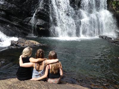 Drie reizigers bij een waterval en natuurlijke zwemplek in Sri Lanka.