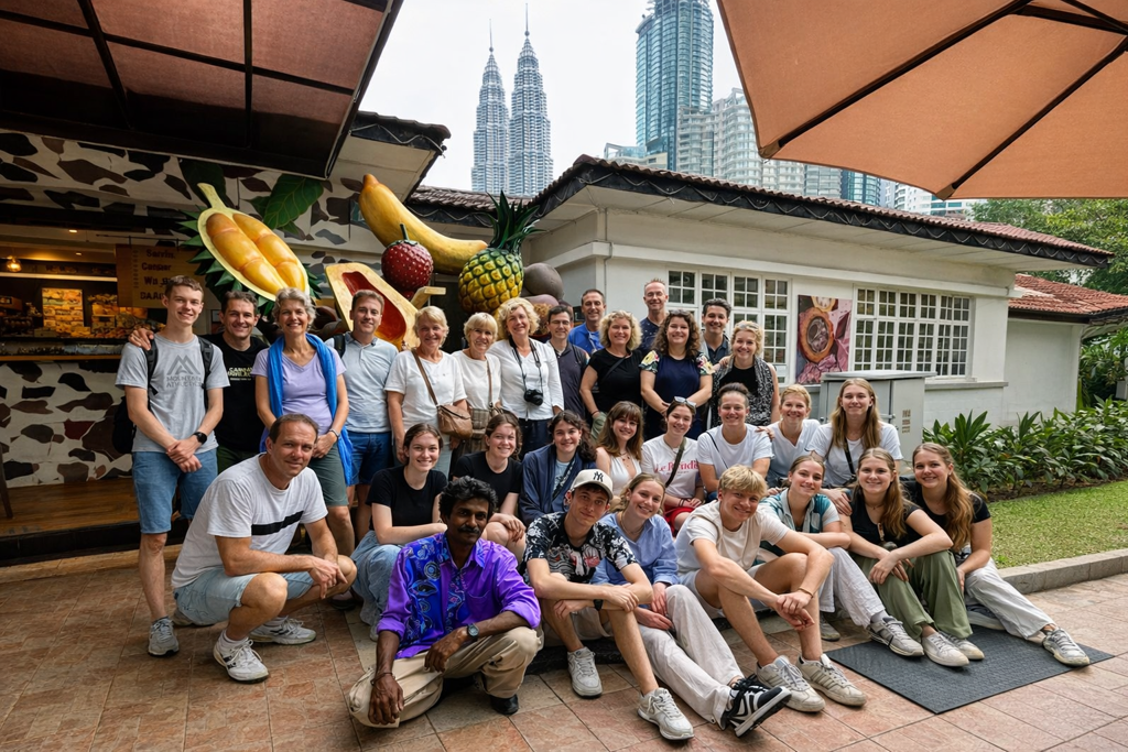 Groepsfoto van deelnemers aan een familiereis in Kuala Lumpur, met de Petronas Twin Towers op de achtergrond.