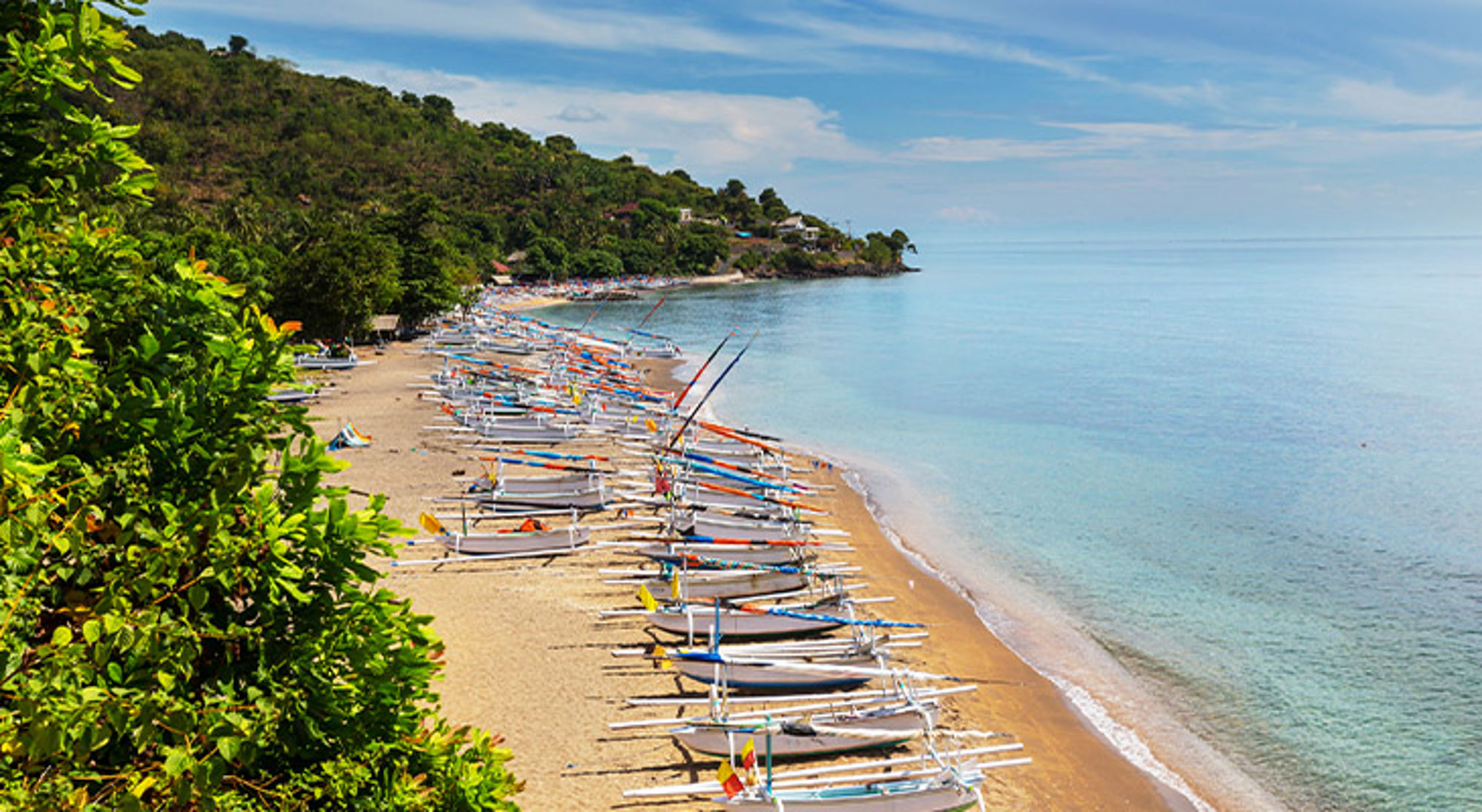 Amed Beach Bali Rij traditionele vissersboten op het zandstrand langs een groene kustlijn met kalme zee.