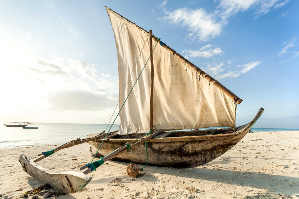 Traditionele dhow met wit zeil op het strand van Zanzibar tijdens familiereis Kenia, Tanzania en Zanzibar.