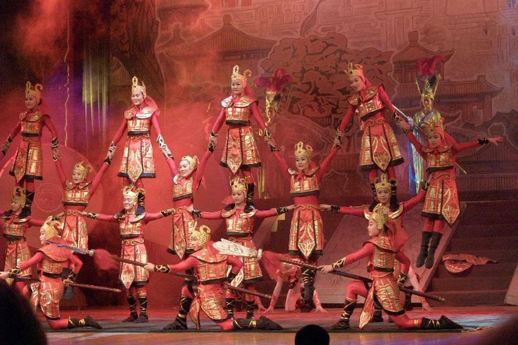 Acrobaten in rood-gouden kostuums tijdens een Chinese show, hoogtepunt van een familiereis China.