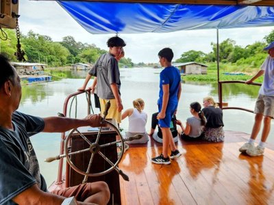 Kinderen spelen in een hangmat bij een houten huis in Thailand tijdens de Familiereis Thailand Comfort-Plus.