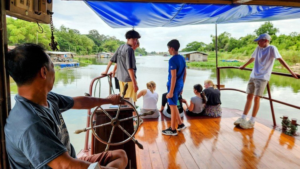 Kinderen spelen in een hangmat bij een houten huis in Thailand tijdens de Familiereis Thailand Comfort-Plus.