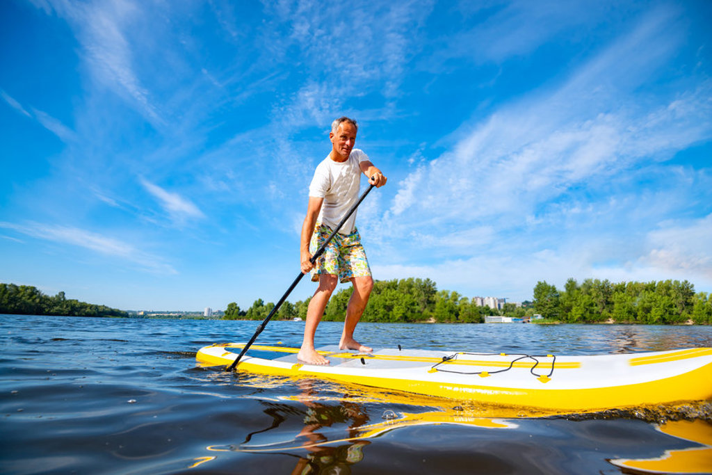Man op een SUP-board op helderblauw water, activiteit tijdens groepsrondreis Zuid-Oost Europa.
