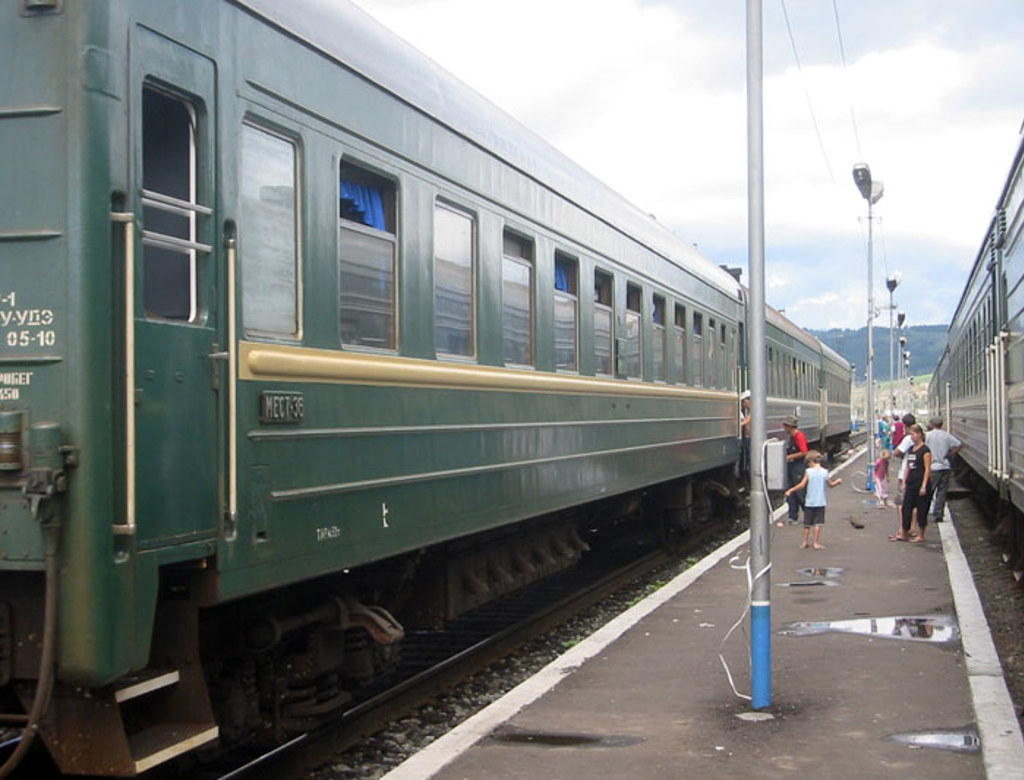 Groene trein op een perron, reizigers stappen in tijdens een groepsrondreis door Rusland.