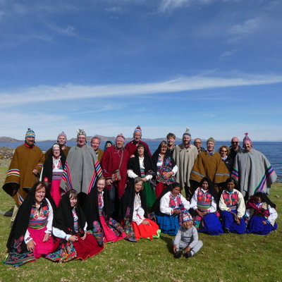 Groepsfoto tijdens groepsrondreis Peru met locals in traditionele kleding aan het Titicacameer.