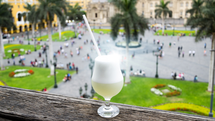 Pisco sour cocktail met uitzicht op Plaza Mayor in Lima, Peru.