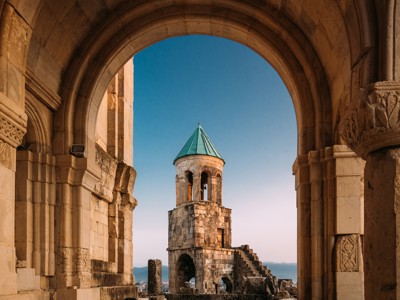 Uitzicht op de klokkentoren van de Bagrati-kathedraal in Kutaisi, Georgië, door een stenen boog.