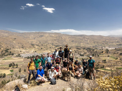 Groep 22-35ers wandelaars poseert op een berg met uitzicht over een vallei in Peru.