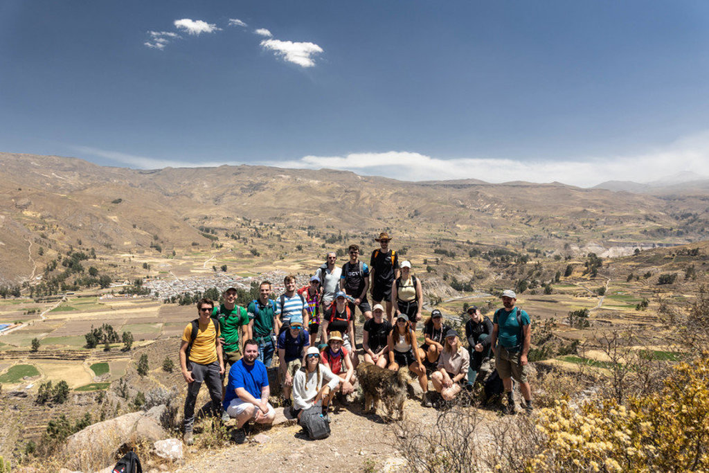 Groep 22-35ers wandelaars poseert op een berg met uitzicht over een vallei in Peru.