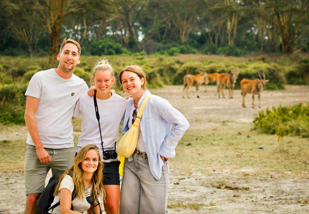 Groep 22-35ers op safari in Kenia en Tanzania met antilopen op de achtergrond.