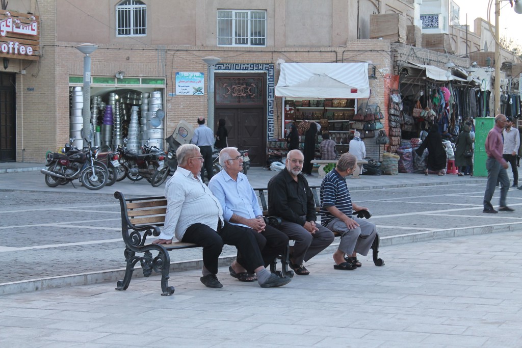 Mannen zitten op een bankje op een plein met marktstalletjes in Iran tijdens een rondreis Iran.