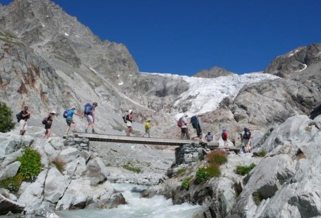 Gezin wandelt in de Franse Écrins bij een chalet tijdens een familiereis.
