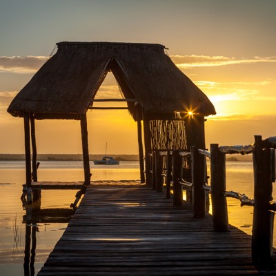 Houten steiger met rieten hut bij zonsondergang aan een lagune in Mexico, tijdens een groepsrondreis.