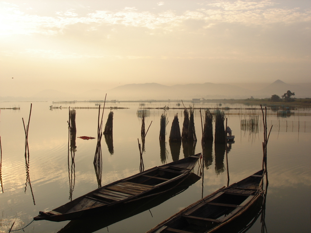 Houten boten op een rustig meer bij zonsopkomst in Orissa, India.