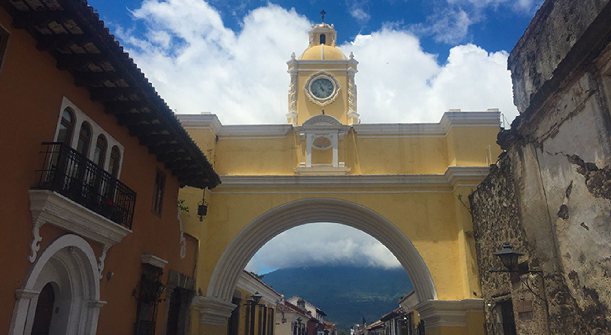 stad antigue in Guatemala Gele boog met kloktoren in Antigua, Guatemala, met straat en vulkaan op de achtergrond.