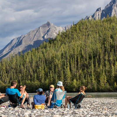 Familie ontspant aan een rivier met uitzicht op de Rocky Mountains tijdens familiereis Canada West.