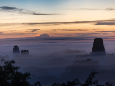 Zonsopkomst boven de nevelige jungle met tempels van Tikal, Guatemala, op de Route Trans Midden Amerika.