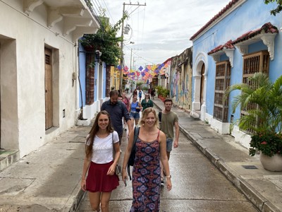 Reizigers wandelen door een kleurrijke straat in Cartagena, Colombia, met vlaggetjes en historische gevels.