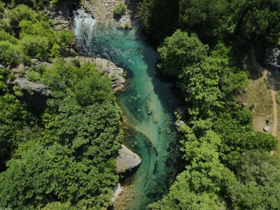 een turquoise rivier met waterval in een groene kloof in Noord-Griekenland.