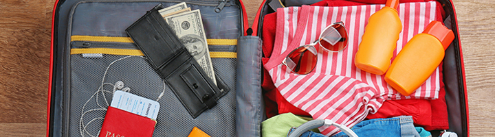 Ingepakte koffer met paspoort, geld, zonnebril, koptelefoon, kleding en zonnebrand voor een goed voorbereide reis.