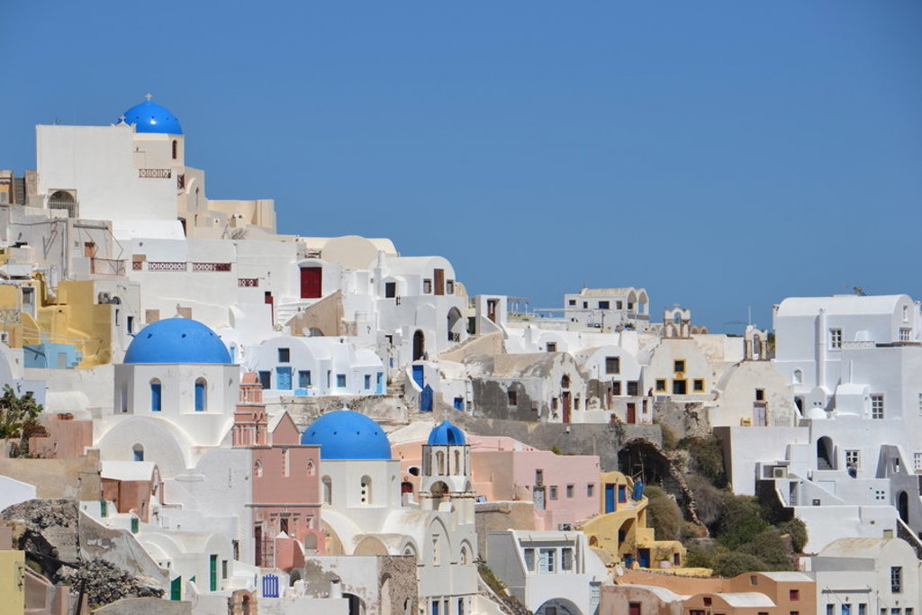 Witte huizen en blauwe koepelkerken in Oia op Santorini tijdens wandelvakantie in Griekenland.
