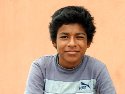Portret van een jongen in Nicaragua tegen een oranje muur.