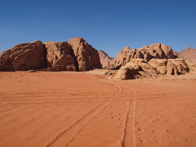 Rode zandvlakte met rotsformaties in de Wadi Rum-woestijn in Jordanië.