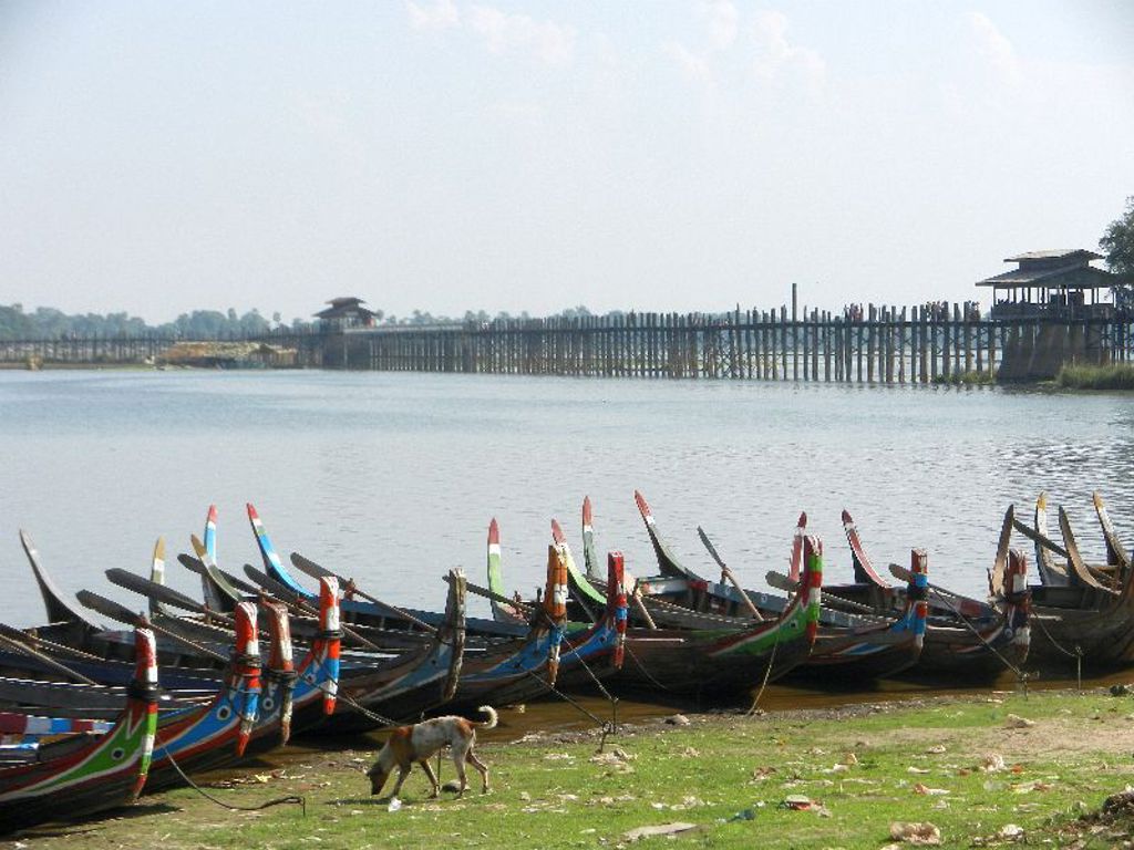 Houten boten aan de oever bij de U Bein-brug in Myanmar tijdens een familiereis.