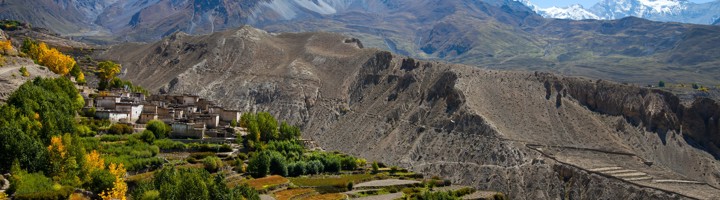 Uitzicht op het Mustang-gebergte in Nepal met een bergdorp, terrassen en besneeuwde Himalayapieken.
