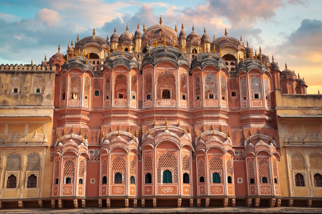 Hawa Mahal (Paleis van de Winden) in Jaipur, Rajasthan, met roze gevel vol ramen en koepels bij zonsondergang.