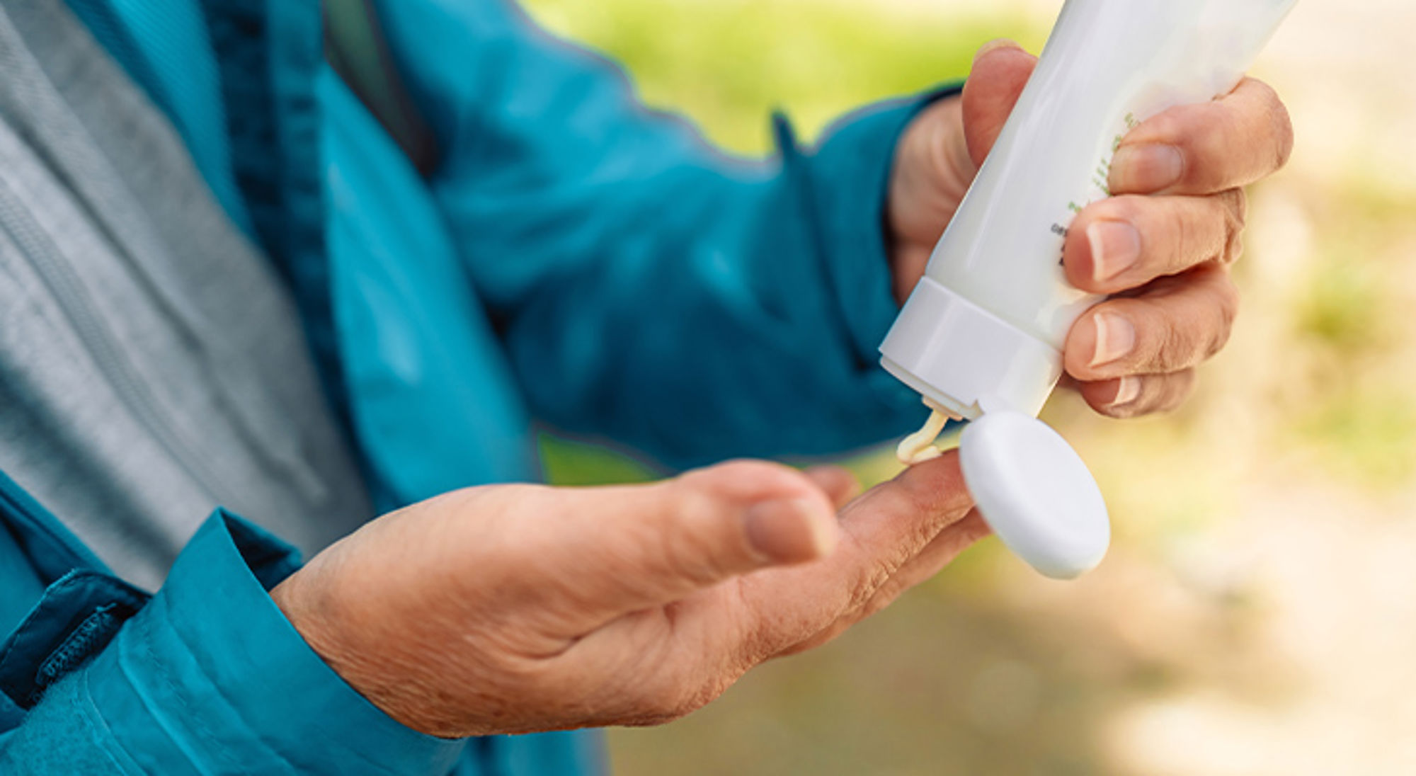 Zonnebrand smeren Handen die zonnebrandcrème uit een fles knijpen voor bescherming tegen de zon tijdens het reizen.