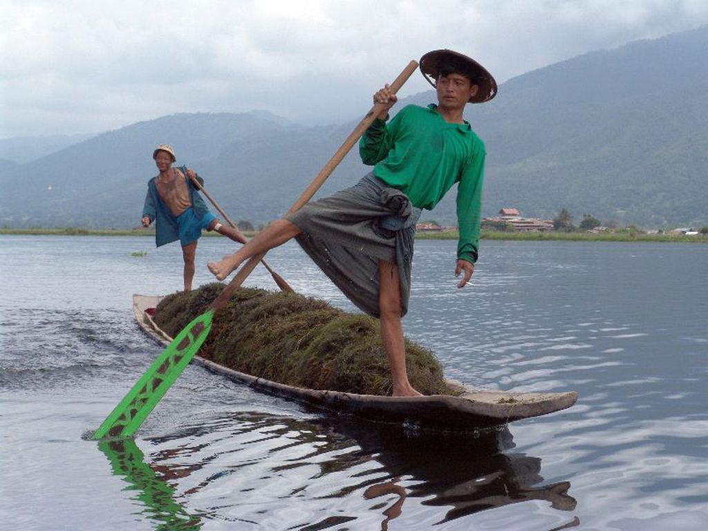 Intha-vissers op het Inlemeer in Myanmar, balancerend op een smalle boot met lange roeispaan.