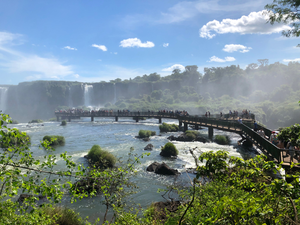 Uitzicht op de Iguazú-watervallen in Brazilië met loopbrug vol bezoekers boven de rivier.