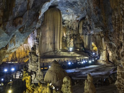 Verlichte grot in Vietnam met stalactieten, stalagmieten en wandelpaden.