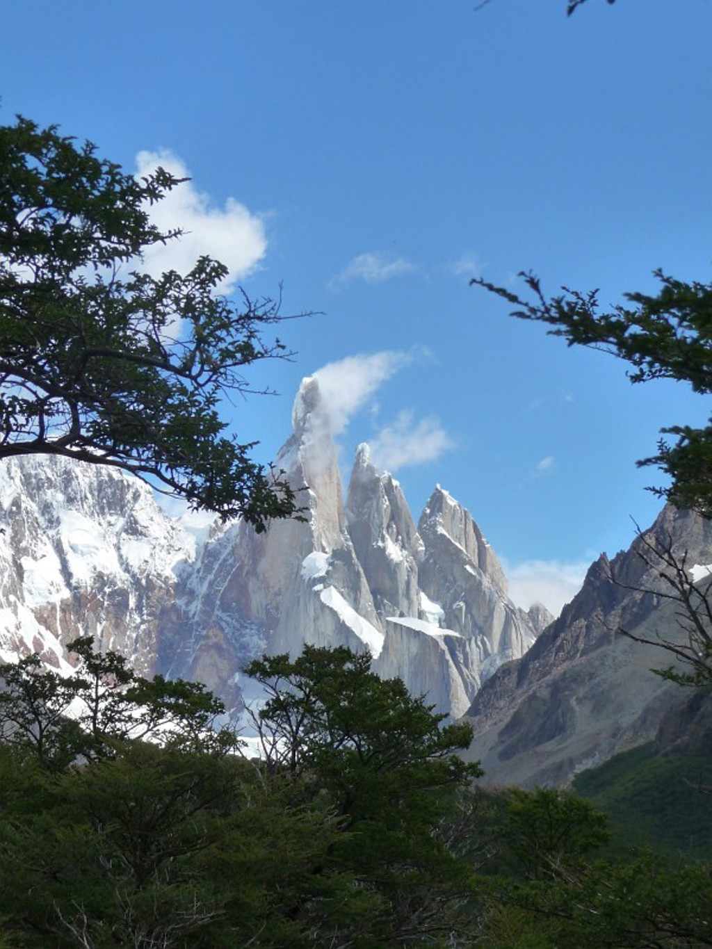 Bergtoppen van het Fitz Roy-massief in Patagonië, Argentinië, met sneeuw en wolken boven het bos.
