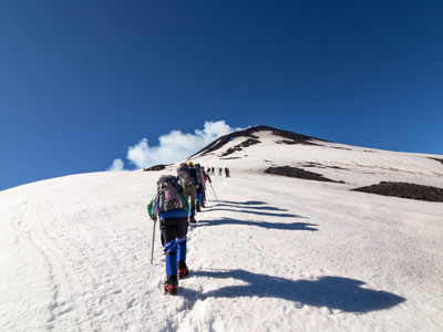Wandelaars klimmen in een rij omhoog over een besneeuwde berghelling in Patagonië.