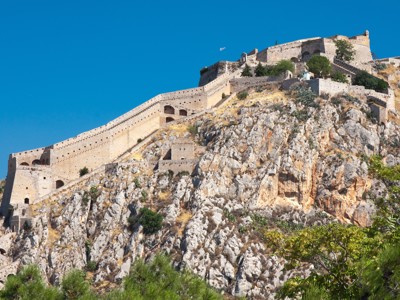 Palamidi-fort boven Nafplio, Griekenland, met stenen muren op een rotsachtige heuvel onder blauwe lucht.