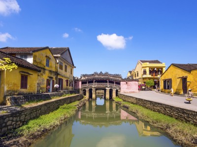 Japanse brug in Hoi An met gele huizen langs het kanaal, Route Vietnam.