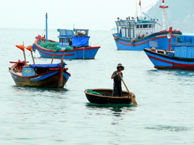 Vissersboten in de baai van Vietnam, met een man in een ronde boot op het water.