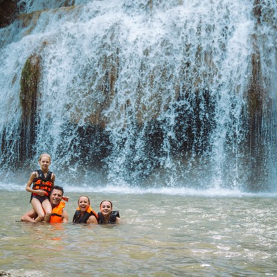 Gezin zwemt bij een waterval in Thailand tijdens de Familiereis Thailand Chill & Adventure.