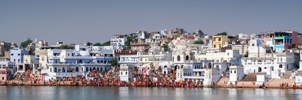 Drukke ghats aan een heilig meer met witte tempels en stad op de achtergrond tijdens een 22-35ers reis India.