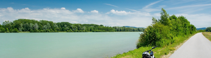 Fiets met fietstassen langs een rivier op een zonnige dag, ideaal voor een fietsvakantie.