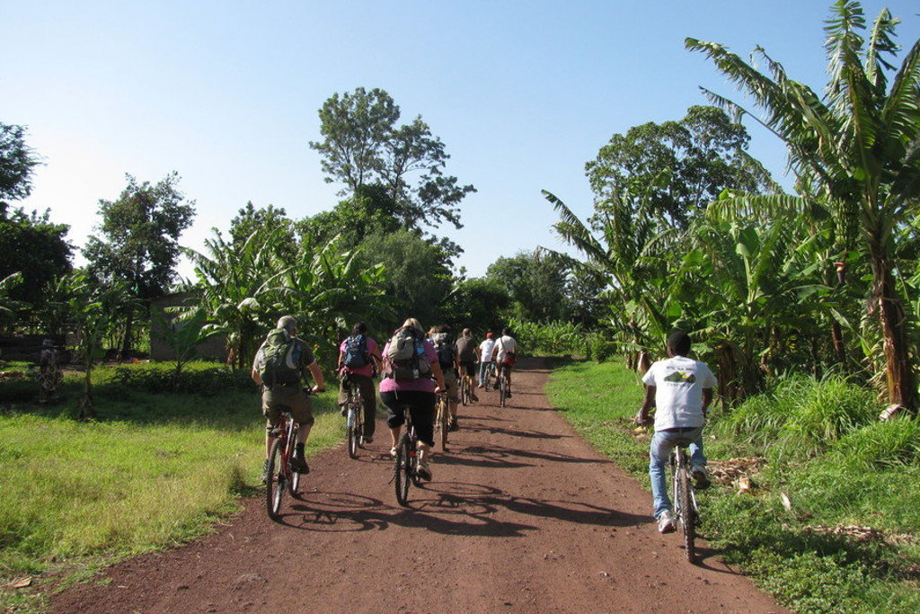 Fietstocht met groep reizigers over een zandweg door groen landschap in Kenia tijdens groepsrondreis Kenia Tanzania Zanzibar.