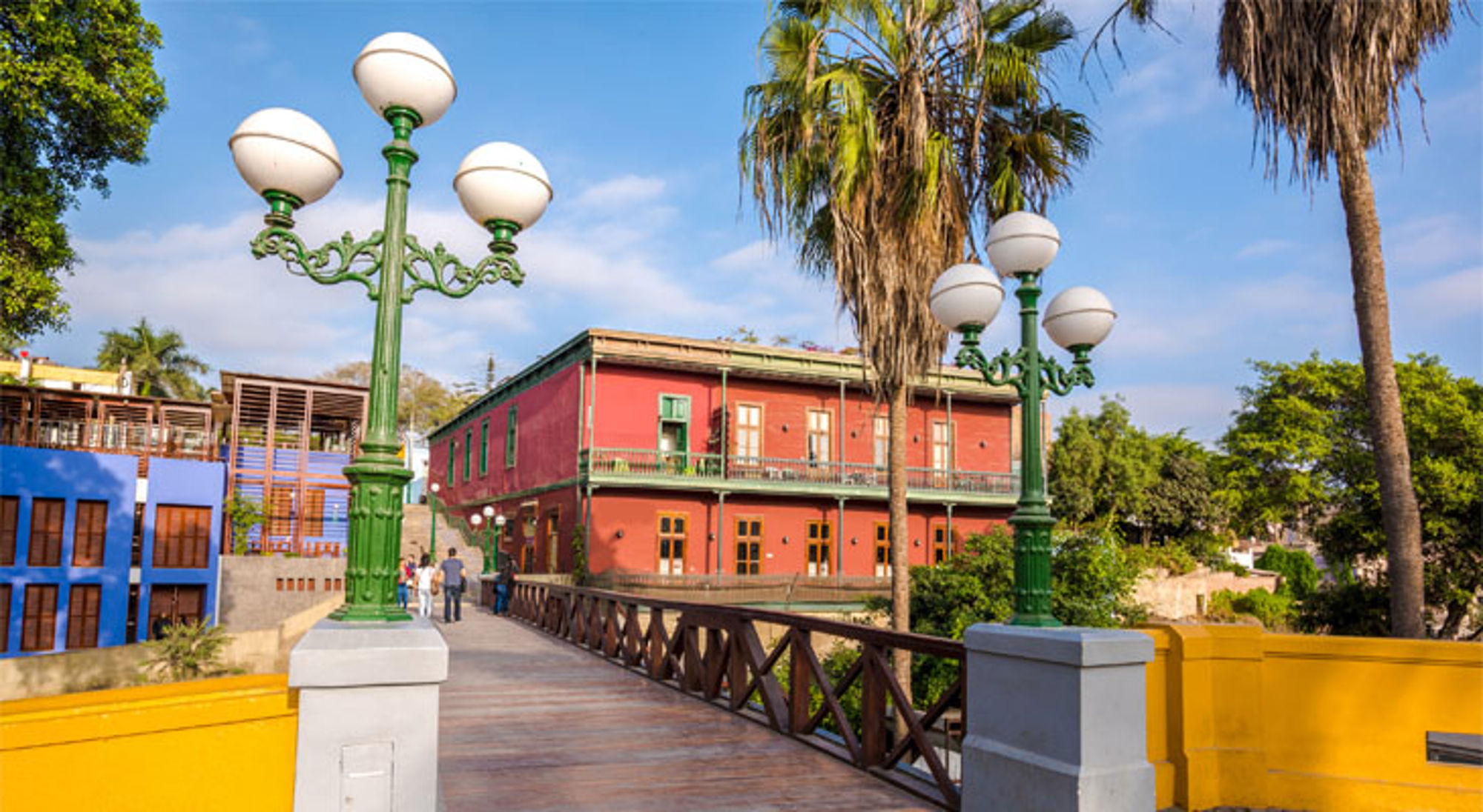 Voetgangersbrug met groene lantaarns en kleurrijke gebouwen in Barranco, Lima, Peru.
