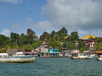 Kustplaats in Guatemala met kleurrijke huizen en vissersboten op zee, op weg naar Copán.